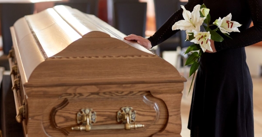 woman at funeral putting her hand on casket